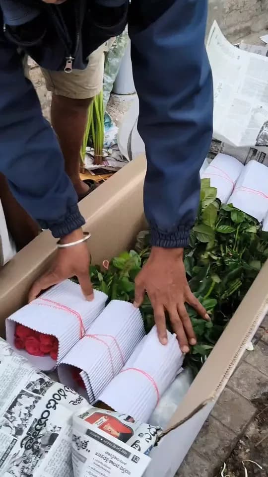 Newspaper-wrapped bunches of flowers and greens are packed into a carton and the box is closed for delivery, at Fresh Stem in Bengaluru.